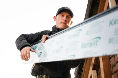Monteur van Top Gevelbekleding met een Keralit gevelplank op de steiger